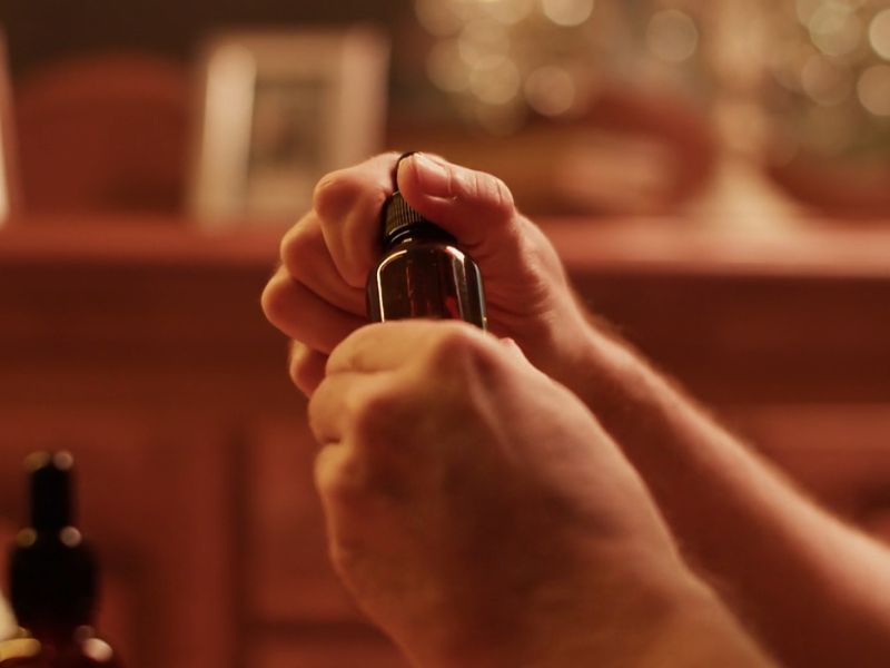 Muškarac otvara bočicu ulja za bradu