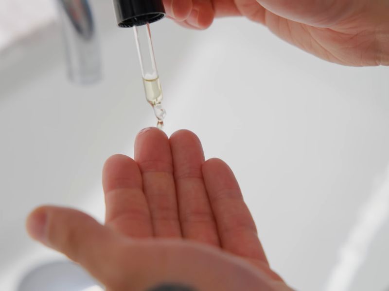 Muškarac stavlja par kapi ulja za bradu na ruku