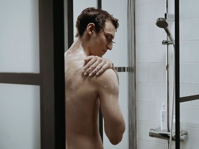 momak u tuš kabini uklanja penu sa svog tela