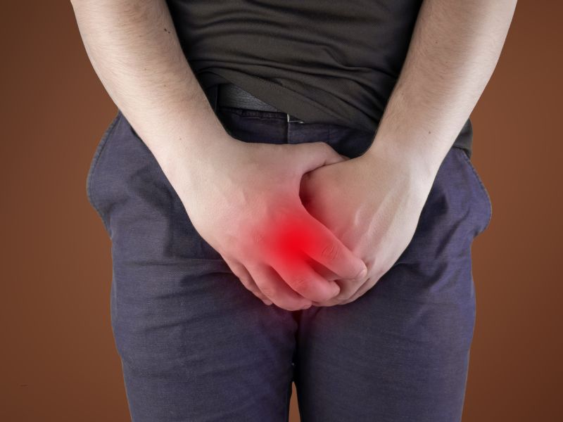 muškarac u odeći se drži "dole" od bola