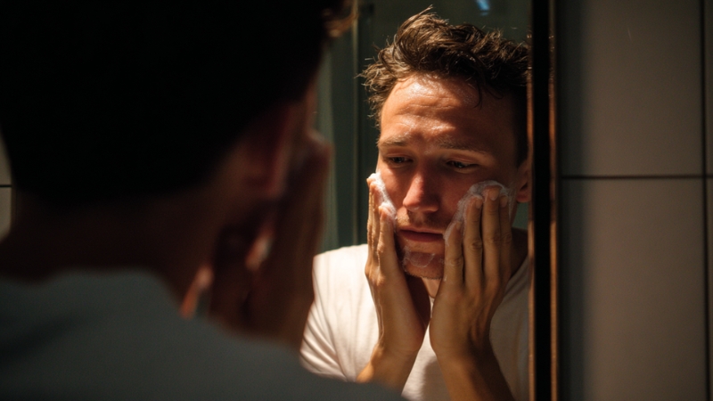 Muškarac ispred ogledala čisti lice