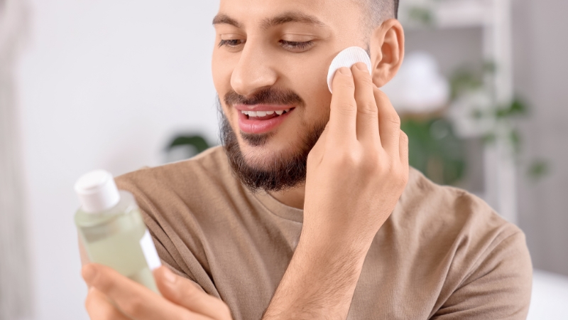 Muškarac drži tonik i nanosi ga tuferom na lice